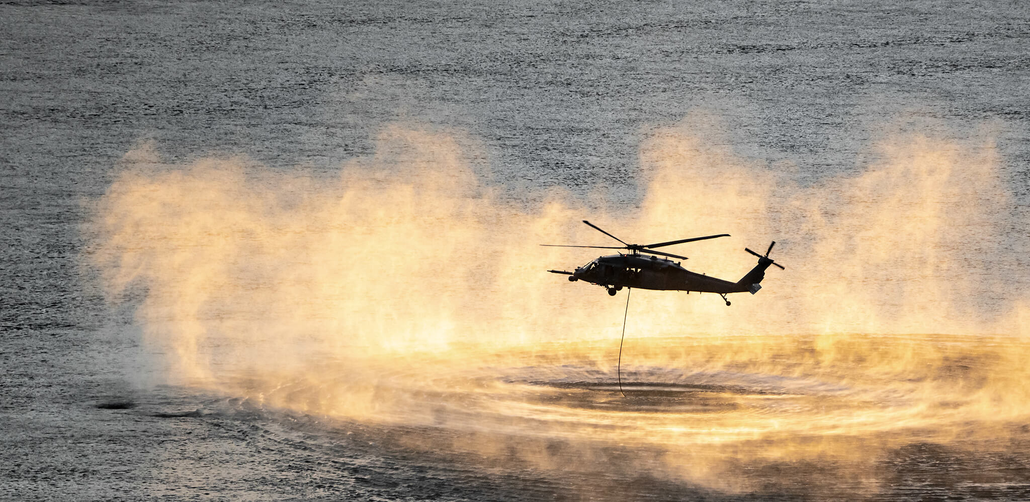 Up close shot of helicopter performing training rescue operation over the columbia river at sunset