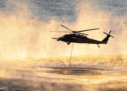 Up close shot of helicopter performing training rescue operation over the columbia river at sunset